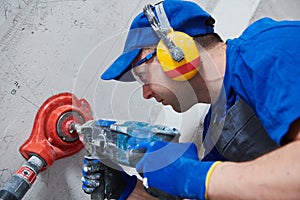 Electrician at work. boring hole for electric outlet by power tool drill. photo