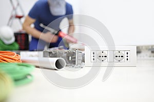 Electrician at work with silicone gun in hand, install socket, electric circuits, electrical wiring