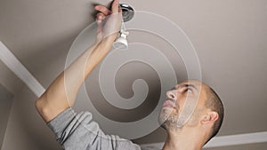 Electrician worker changes electric LED light bulb on the ceiling