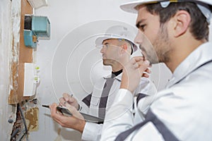 Electrician workers checking voltage fuse board