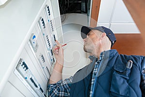 Electrician working with electric scheme plan in front fuse-switch-board