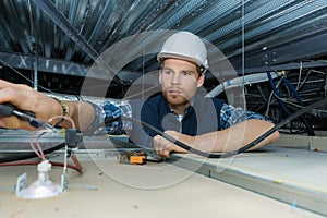 Electrician working with electric wires in factory