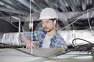 Electrician working through open ceiling hatch