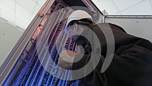 Electrician working with wiring on electrical box, fixing connections. Action. Bottom view of an electrician in a