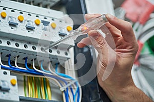 Electrician works with electric meter tester in fuse box