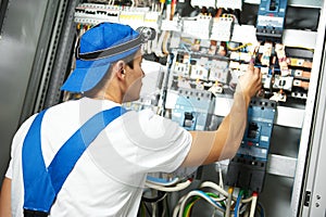 Electrician works with electric meter tester in fuse box