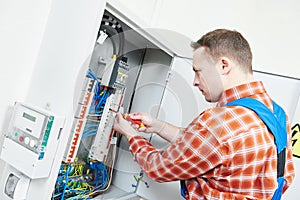 Electrician works with electric meter tester in fuse box