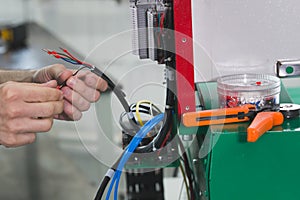 Electrician works with parts of energy equipment on plant