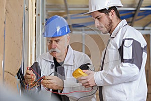Electricians checking socket voltage with digital multimeter