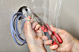 Electricians clears the ends of wires using pliers, hands close-up.