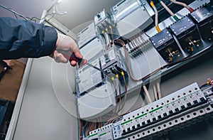 Electricians hands testing switches in electric box. Electrical panel with fuses