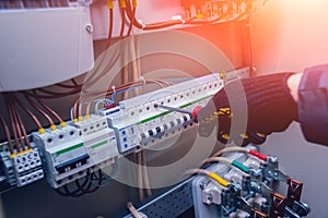 Electricians hands testing switches in electric box. Electrical panel with fuses