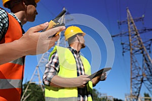 Electricians near high voltage towers, focus on hand with portable radio station