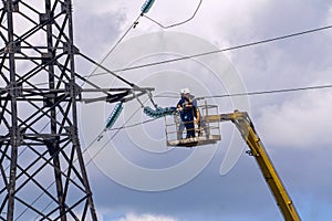 electricians are repairing a high-voltage line against the background of a blue sky
