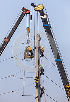 Electricians repairing wire on electricity power pole with hydraulic platform.