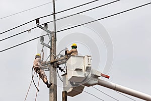 Electricians repairing wire of the power line with bucket hydraulic lifting platform