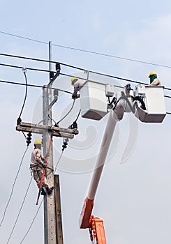 Electricians repairing wire of the power line with bucket hydraulic lifting platform