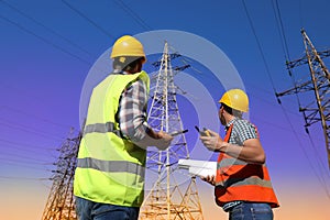 Electricians in uniforms near high voltage towers