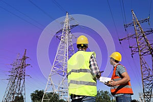 Electricians in uniforms near high voltage towers