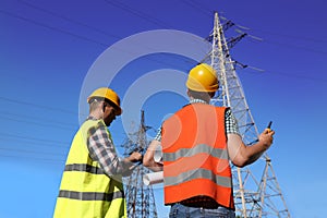 Electricians in uniforms near high voltage towers