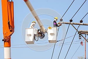 Electricians working to repair the power line under light blue sky