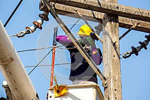 Electricians working to repair the power line under light blue sky background