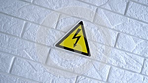 Electricity danger a sign on yellow background. A danger sign hangs on a wall. 4k stock footage.