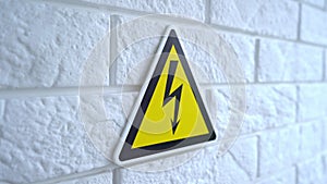 Electricity danger a sign on yellow background. A danger sign hangs on a wall. 4k stock footage.