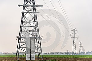 Electricity distribution system. High voltage overhead power line, power pylon, steel lattice tower standing in the field.