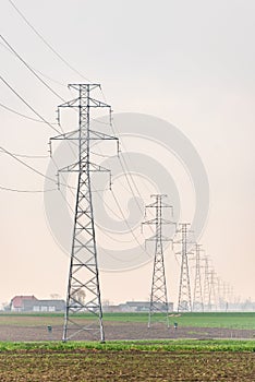 Electricity distribution system. High voltage overhead power line, power pylon, steel lattice tower standing in the field.