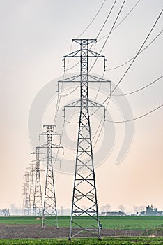 Electricity distribution system. High voltage overhead power line, power pylon, steel lattice tower standing in the field.