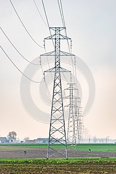 Electricity distribution system. High voltage overhead power line, power pylon, steel lattice tower standing in the field.