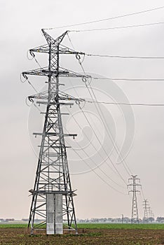 Electricity distribution system. High voltage overhead power line, power pylon, steel lattice tower standing in the field. Blue