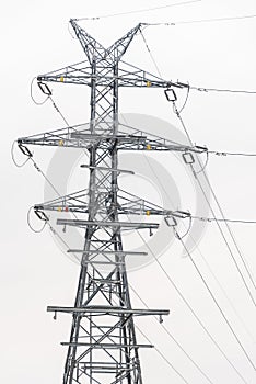 Electricity distribution system. High voltage overhead power line, power pylon, steel lattice tower standing in the field. Blue