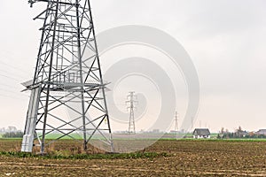 Electricity distribution system. High voltage overhead power line, power pylon, steel lattice tower standing in the field. Blue