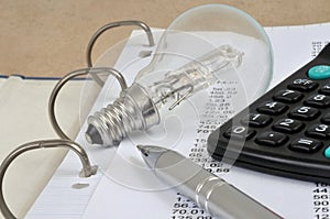 Electricity expenditure concept with an electric bulb, a calculator and numbers