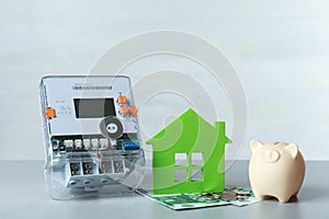 Electricity meter, piggy bank and euro banknotes on grey table