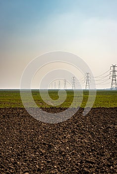 Electricity pole with high tension power transmission cable in green fields of countryside area