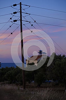 Electricity pole and a house with hot water supply on the roof