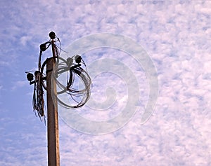 Electricity power pole with many disconnected wires on blue cloudy sky background.