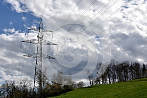 Electricity or power transmission pylon of high voltage with wires in Swiss countryside, village Birmensdorf.