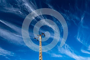 Electricity pylon against dark blue sky with white clouds