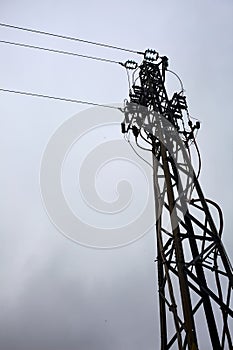 Electricity pylon with over head cables passing on it and a cloudy sky as background