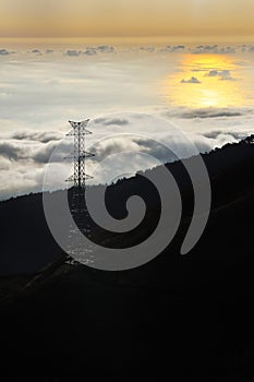 Electricity pylon over valley at sunset, Lomba das