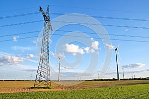 Electricity pylon with overhead lines and wind turbines