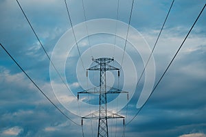 Electricity pylon with overhead powerline cables against cloudy sky