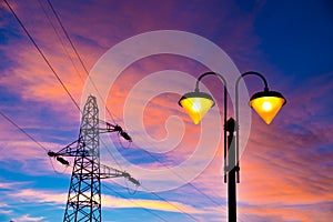 Electricity pylon and streetlamp at sunset