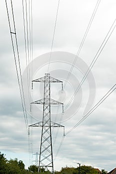 Electricity pylons against a blue and white sky. Large grey pylon with earth wire and electrical conductors.