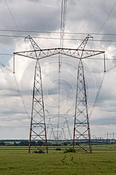 Electricity pylons and cable lines against cloudy sky