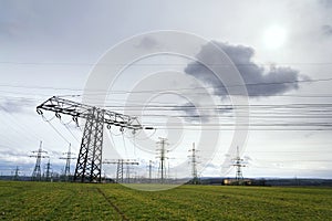 Electricity pylons conducting current from distribution power station with dramatic cloudy sky copy space